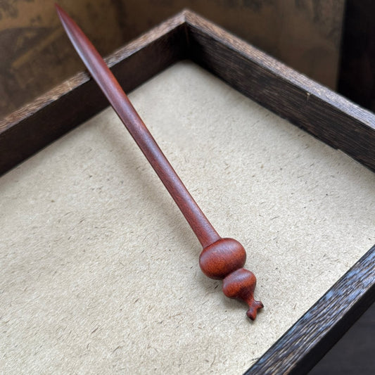 Natural jujube wood hair stick with gourd (hulu) design in wooden tray on textured background.