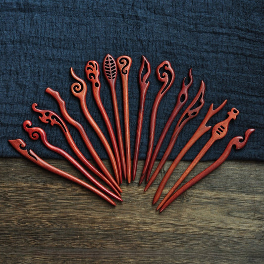 Collection of polished red sandalwood hairpins featuring flame, cloud, leaf, and swirl motifs in deep red tone