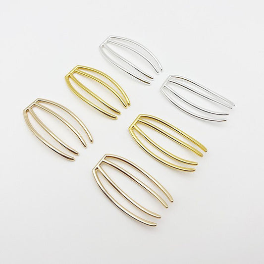 An assortment of four-prong metal hair forks in both gold and silver finishes, used as craft supplies.