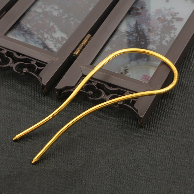 Side profile of a gold alloy arched hair fork, demonstrating its sturdy construction for holding updos.