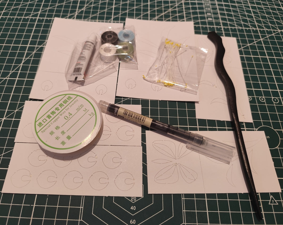 A complete DIY kit for making a traditional Chinese Chanhua flower hairpin. Contents include spools of silk thread, copper wire, a hairpin base, and paper templates laid out on a green cutting mat.