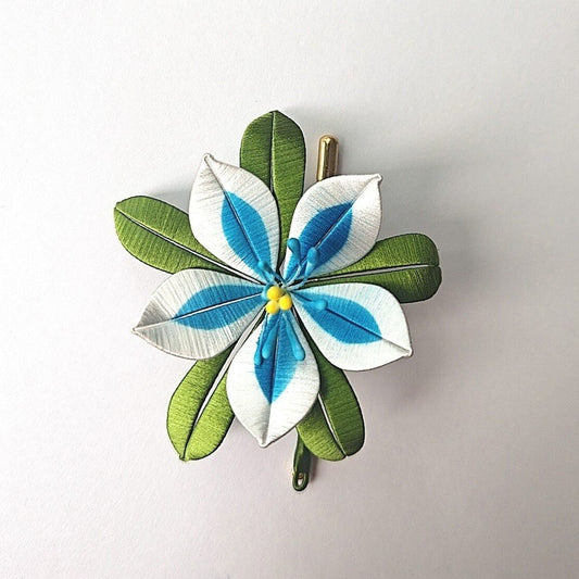 Handcrafted Chanhua Silent Princess brooch featuring white and blue thread-wrapped petals with green leaves and yellow stamens.