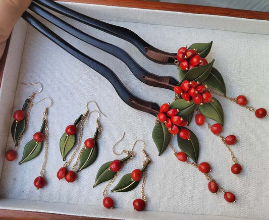 A collection of handmade Chanhua thread-wrapped red bean jewelry, including three pairs of dangle earrings and three matching hairpins with green leaves and red bead tassels.