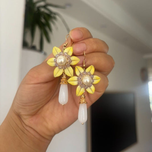 Handheld view of handmade Chanhua thread-wrapped sunflower earrings featuring yellow gradient petals, pearl centers, and white teardrop dangles.