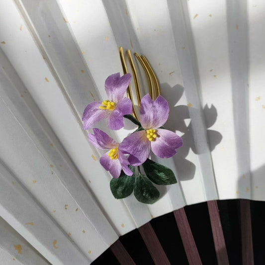 3D silk velvet flower hair accessory depicting blooming violets made with traditional artisanal Ronghua techniques on a gold-tone comb.