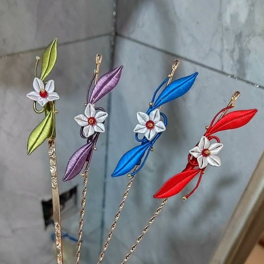 A collection of four Chanhua thread-wrapped hairpins in green, purple, blue, and red, each featuring a delicate white floral blossom.
