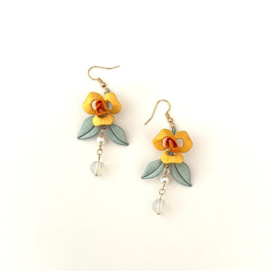 A pair of handmade Chanhua thread-wrapped yellow rose earrings with sage-green leaves, pearls, and glass bead dangles on a white background.