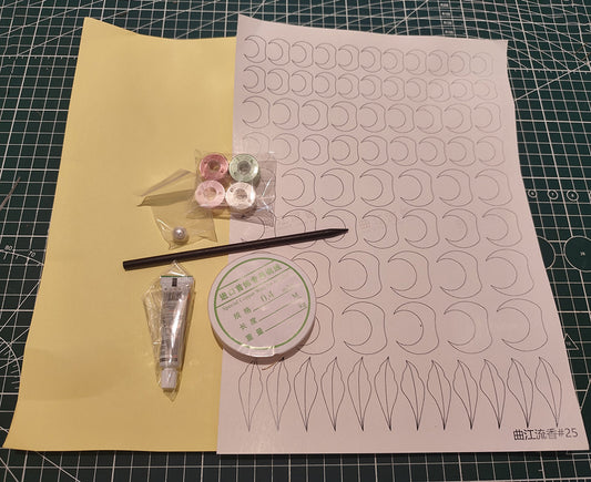 Flat lay of the Chanhua hairpin DIY kit contents, including colored silk threads, copper wire, patterns, a pearl, glue, and a hairpin stick on a craft mat.