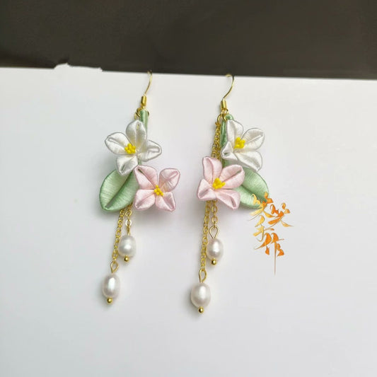 Elegant Chanhua flower dangle earrings featuring handmade white and pink silk flowers, green leaves, and natural freshwater pearls on a white background.