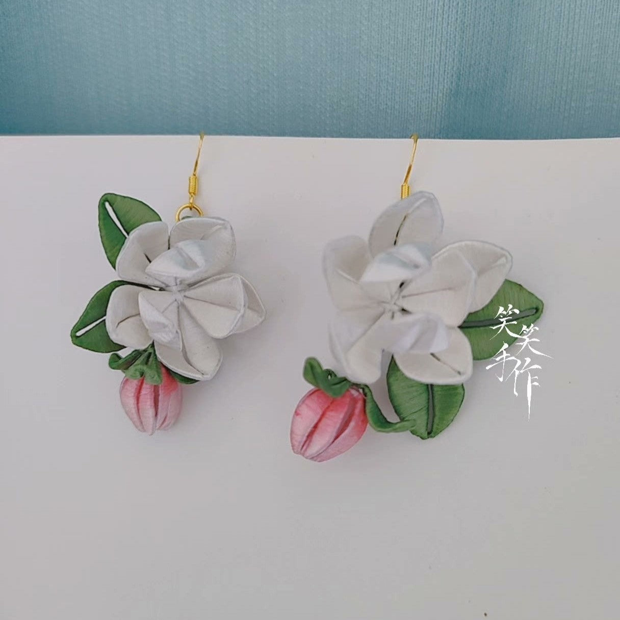 Side view of the unique handcrafted Chanhua flower earrings, emphasizing the dimensional design of the white blossoms and pink buds, with 925 sterling silver ear hooks clearly visible.