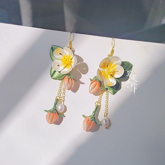 Pair of handcrafted Camellia (Chanhua) earrings made with silk fabric, featuring sterling silver hooks and natural pearls, illuminated by natural light with soft shadows, highlighting their delicate design.