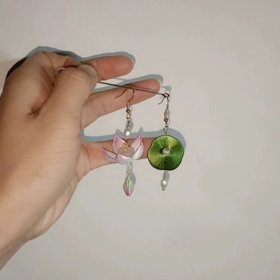Handcrafted asymmetric earrings featuring a delicate pink Chanhua lotus flower and a green lotus leaf with a pearl accent.