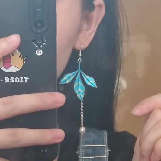 Side view of a person wearing a handmade blue Chanhua leaf dangle earring, showcasing the earring's length and movement against the hair and neck.