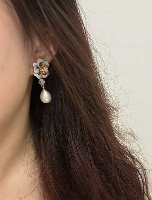 Close-up of a person wearing a single silver handcrafted Chanhua floral drop earring with a pearl pendant.
