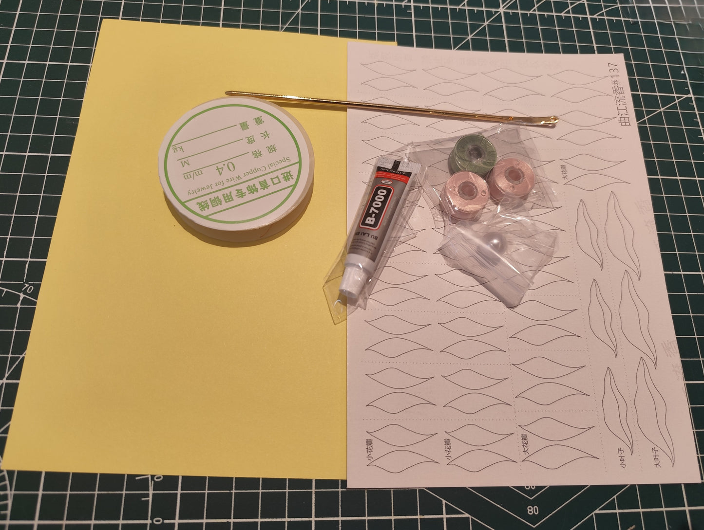 The complete contents of the lotus flower Chanhua DIY kit, including velvet threads, copper wire, glue, hairpin, and paper templates on a craft mat.