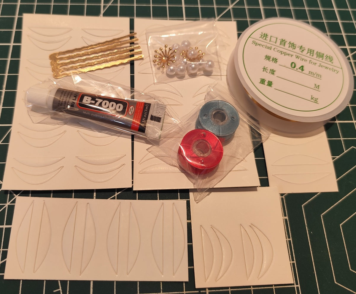 An overhead view of the Chanhua hairpin DIY kit contents, including pre-cut petals, copper wire, craft glue, beads, and a hair comb base on a grid mat.