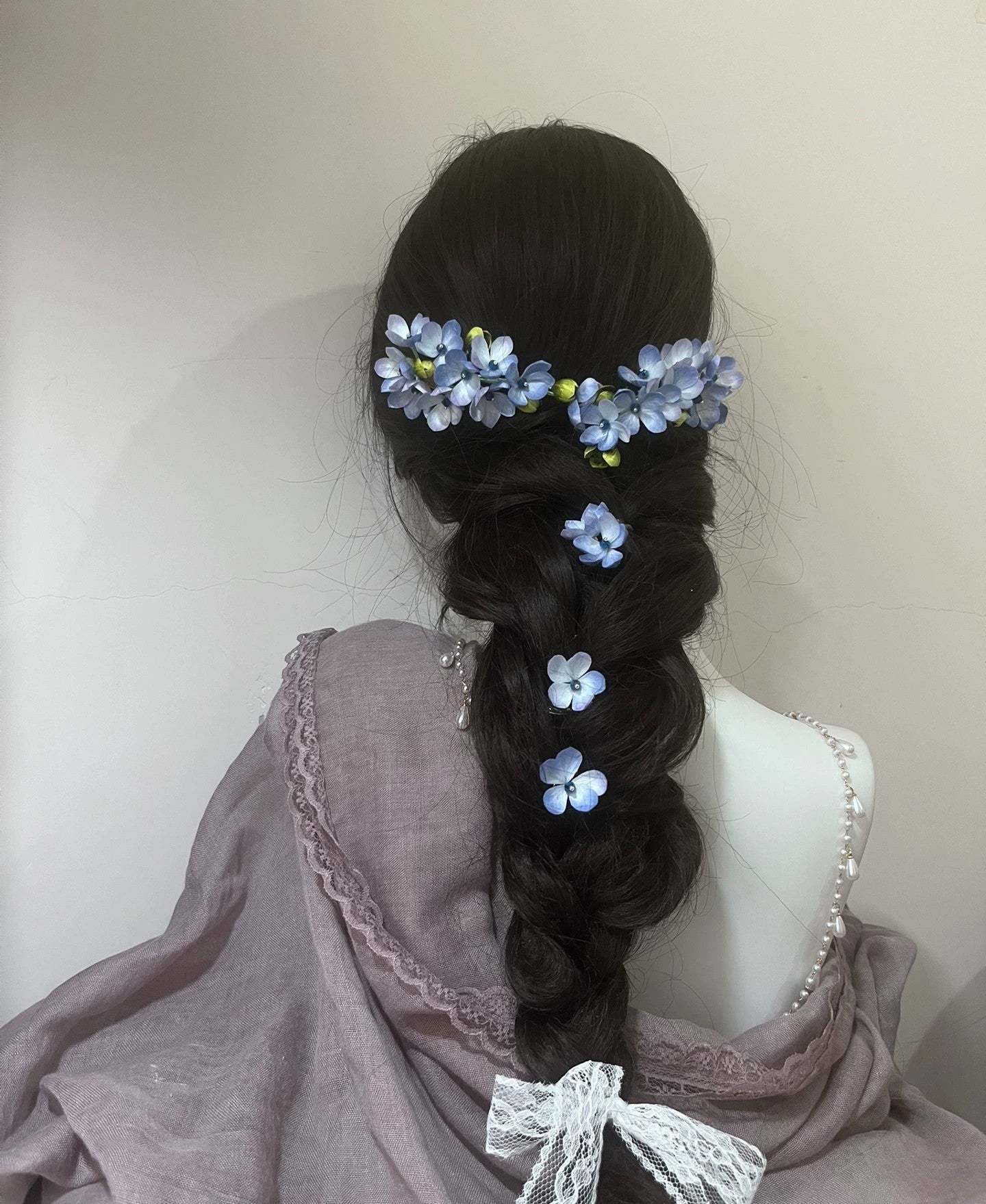 Handcrafted blue mulberry silk Ronghua flower hair accessory woven into a long, dark braided hairstyle, suitable for formal events.