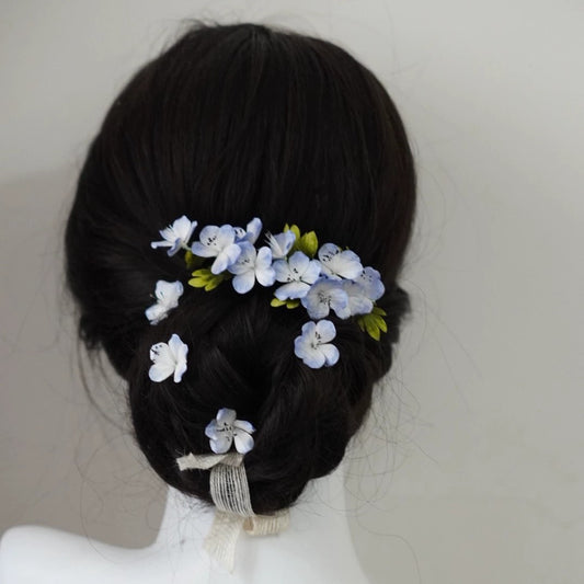 lose-up of handmade blue and white mulberry silk Ronghua flowers pinned into a dark braided hairstyle, highlighting the delicate texture.