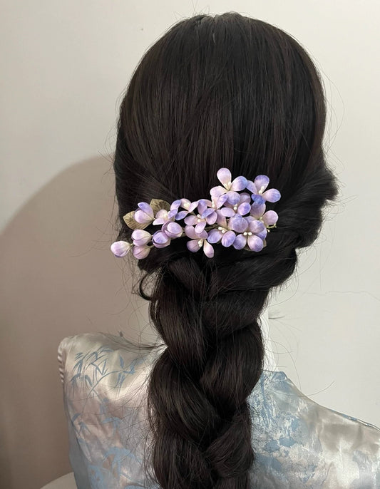 Elegant updo secured with a dark hair stick and adorned with a handmade lilac silk Ronghua flower pin, showcasing traditional styling.