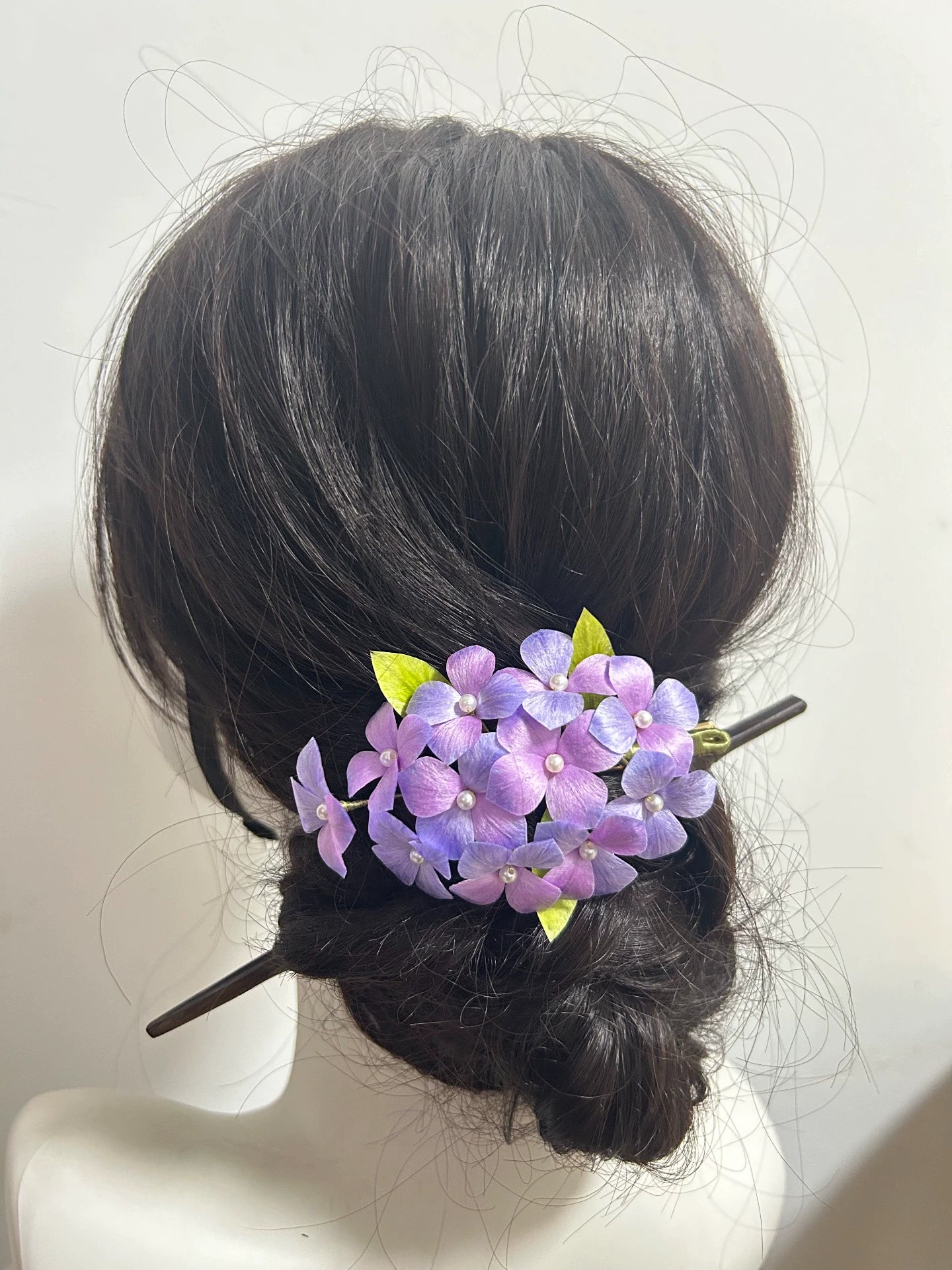 Purple silk hydrangea Ronghua hair clip attached to hair bun on mannequin side view