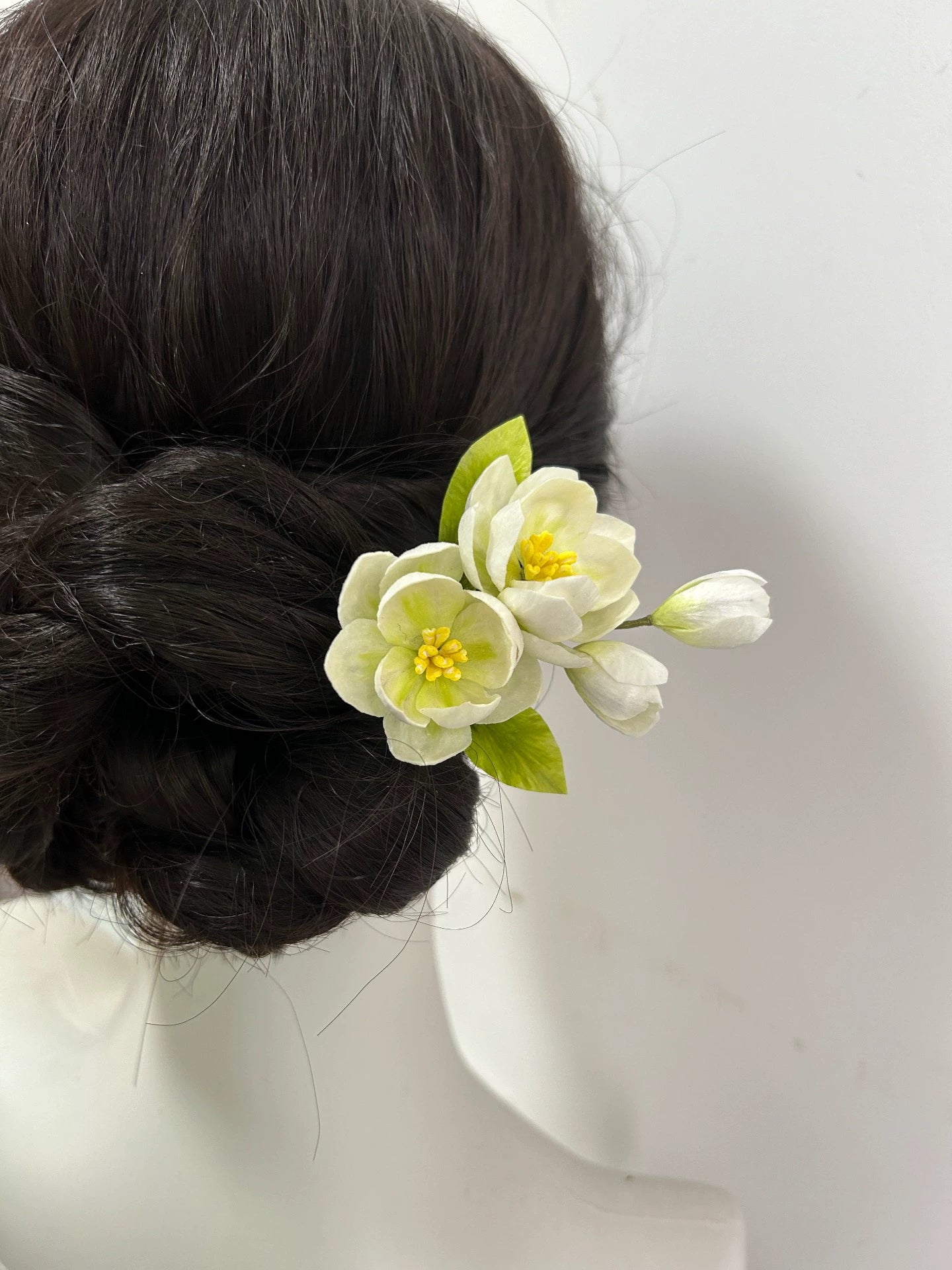 Side view of handmade white jasmine silk hair stick in updo on mannequin.