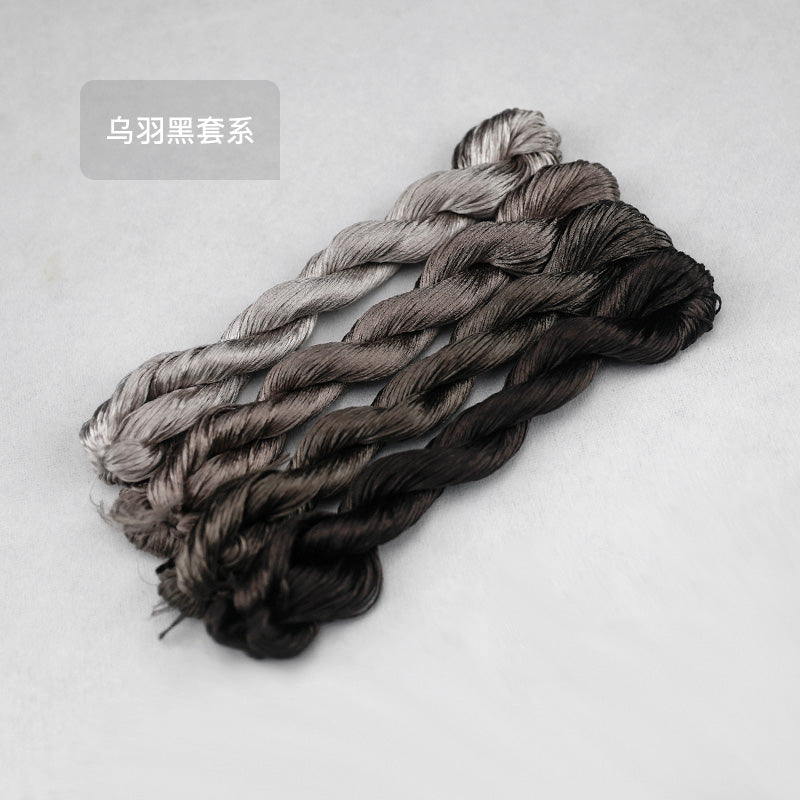 Four skeins of Suzhou embroidery thread in the 'Crow Feather Black' (Wū Yǔ Hēi) series, showing a subtle gradient from silvery grey to a deep, natural black.