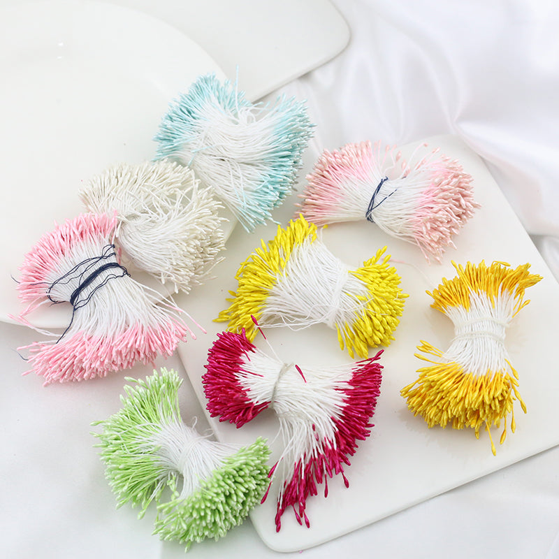 Assorted color bundles of 1.5mm double head pearlescent flower stamens for crafting laid out on a white surface.