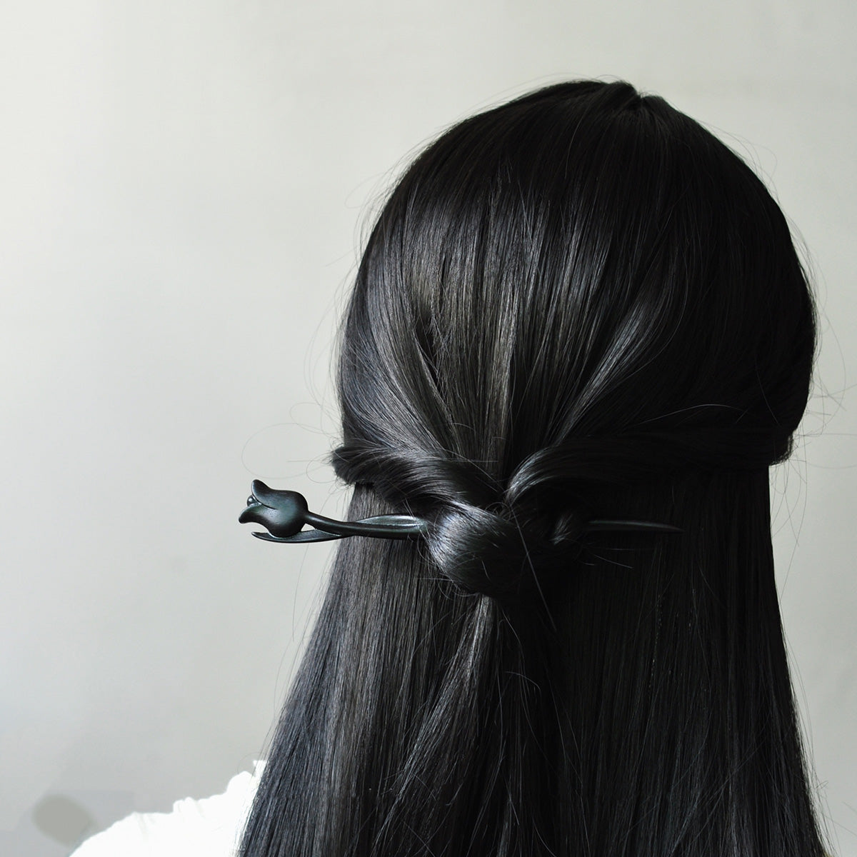Back view of the hand-carved violet sandalwood tulip hairpin holding an elegant updo in dark hair.