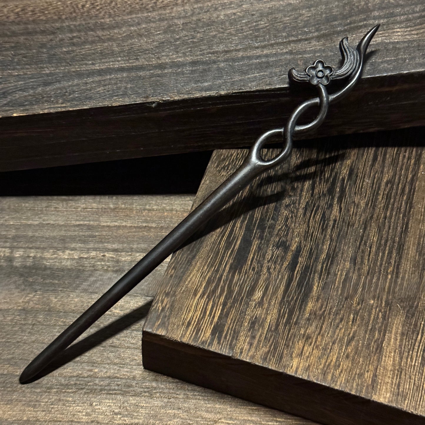 Natural African Blackwood hair stick with 18cm secluded orchid carved design on wooden background.