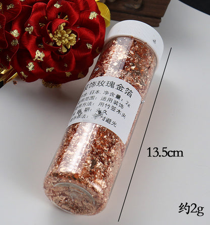 A 13.5cm jar containing 2g of shiny rose gold flakes for gilding and artistic embellishments.