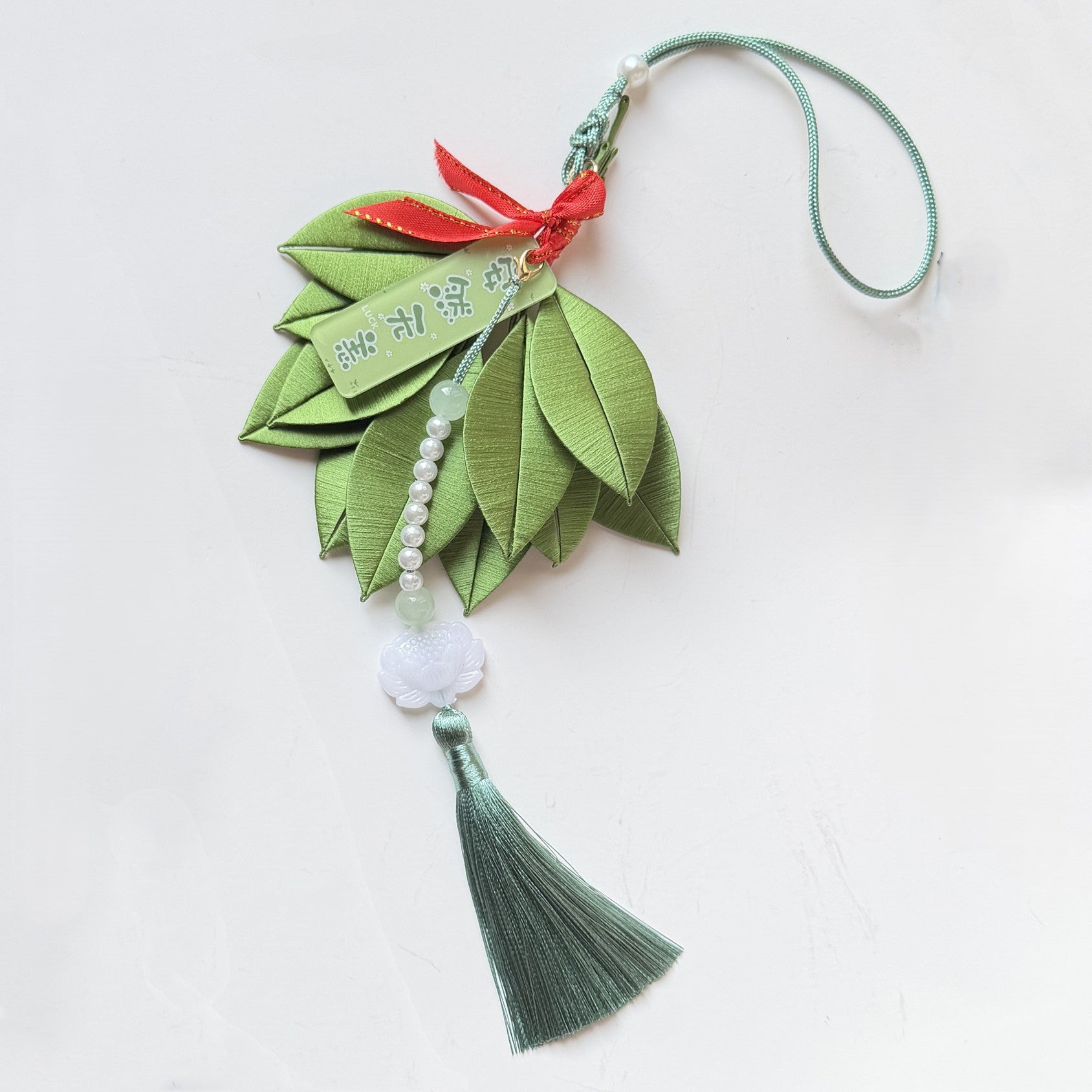 Handmade silk wrapped pomelo leaf car hanging ornament, featuring pearl string and jade lotus tassel.