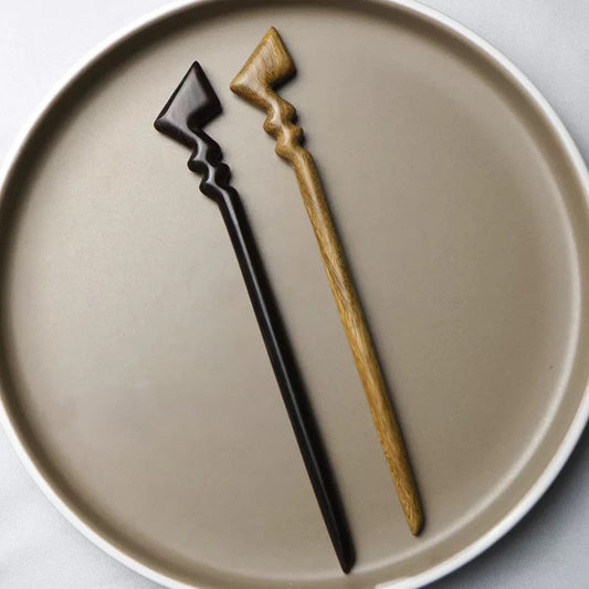 Two natural wooden hair sticks in African Blackwood and Green Sandalwood with Pikachu-inspired zigzag designs on a neutral plate background.