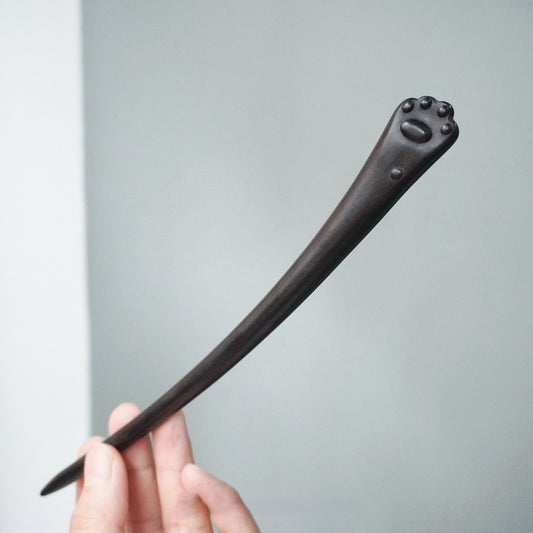Natural African blackwood 20cm hair stick with cat paw design held in hand against neutral background
