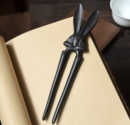 Natural African Blackwood hair stick "Xia Tu" (Heroic Rabbit) design on open book background.