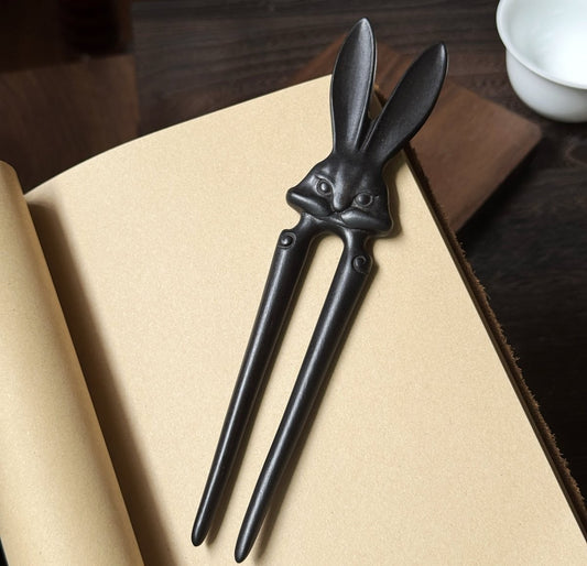 Natural African Blackwood hair stick "Xia Tu" (Heroic Rabbit) design on open book background.