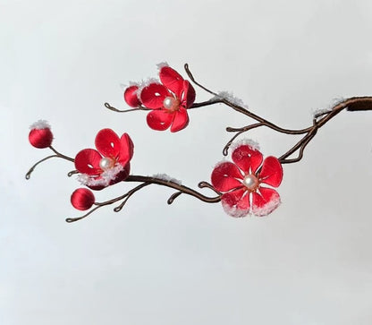 Finished silk-wrapped red Plum Blossom hairpin on a wooden stick with realistic artificial snow details, a handmade DIY flower craft.
