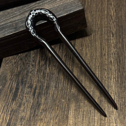 Natural African Blackwood hair stick with Sun God design 14cm on wooden background.