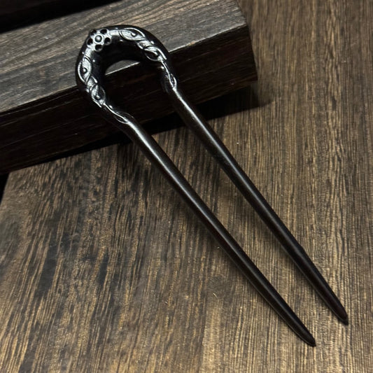 Natural African Blackwood hair stick with Sun God design 14cm on wooden background.