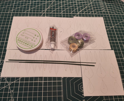The materials for the Iris Chanhua DIY flower kit, including spools of thread, copper wire, paper templates, and floral stems, laid out on a craft mat.