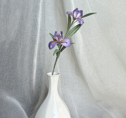 A finished handmade purple Chanhua iris flower with green leaves, created with a DIY craft kit, displayed elegantly in a white vase.