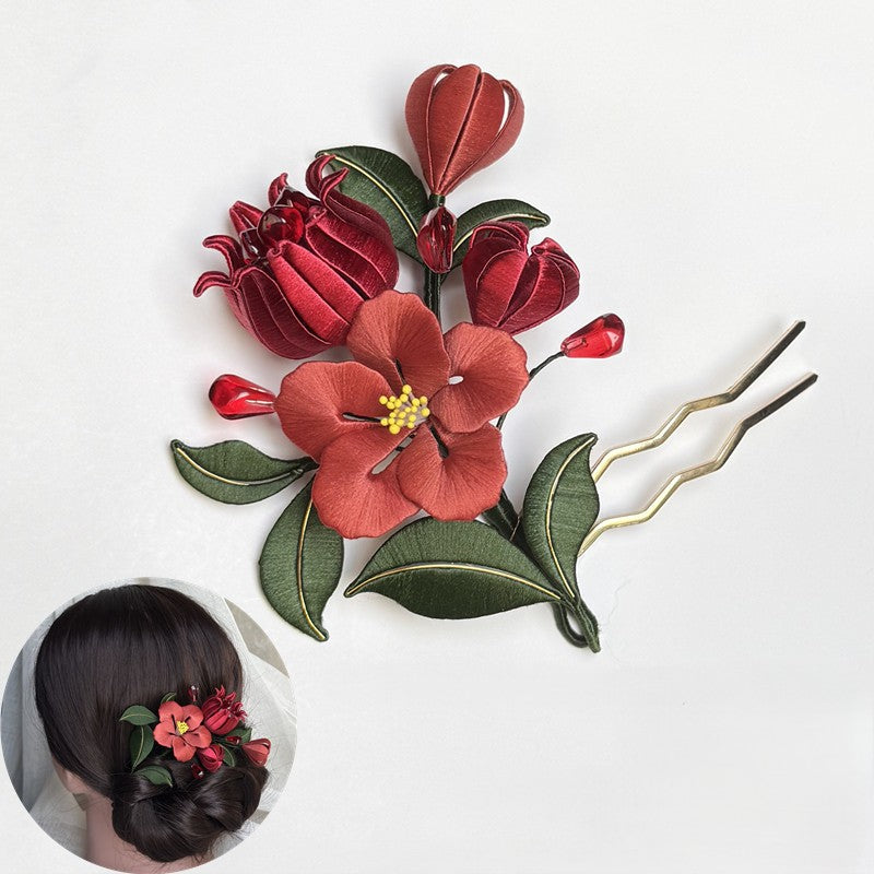 Close-up of a finished handmade red pomegranate flower silk hairpin styled in a classic low bun hairstyle.