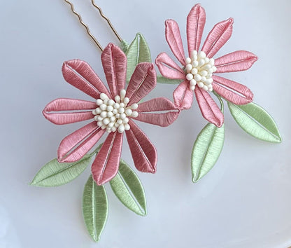 A finished handmade Sun Flower Chanhua hairpin with delicate pink petals and light green leaves, created from a DIY flower craft kit.