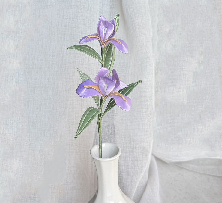 A finished handmade purple Chanhua iris flower with green leaves, created with a DIY craft kit, displayed elegantly in a white vase.