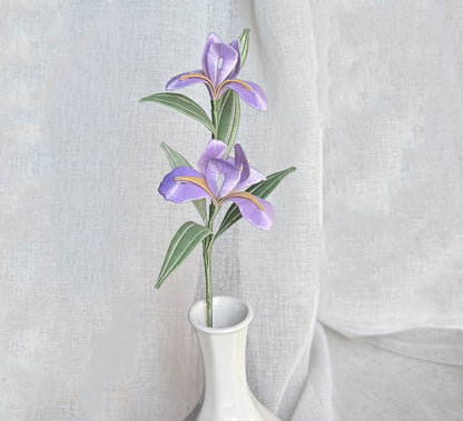 A finished handmade purple Chanhua iris flower with green leaves, created with a DIY craft kit, displayed elegantly in a white vase.
