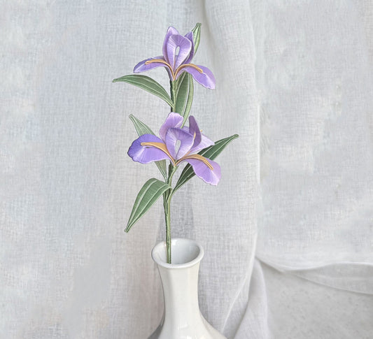 A finished handmade purple Chanhua iris flower with green leaves, created with a DIY craft kit, displayed elegantly in a white vase.