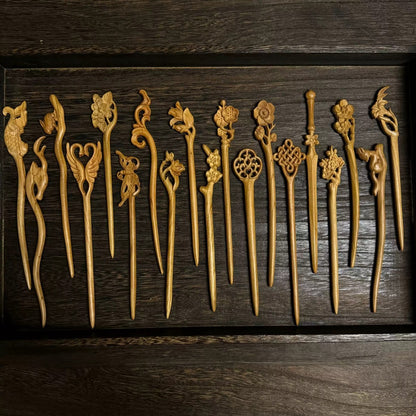 Set of natural peach wood hair sticks with assorted floral, bird, and nature carvings displayed in wooden tray