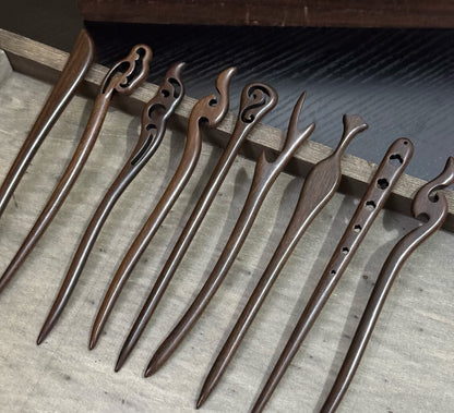 Set of 10 natural rosewood hair sticks with carved designs, approx. 18cm length, arranged in wooden tray.