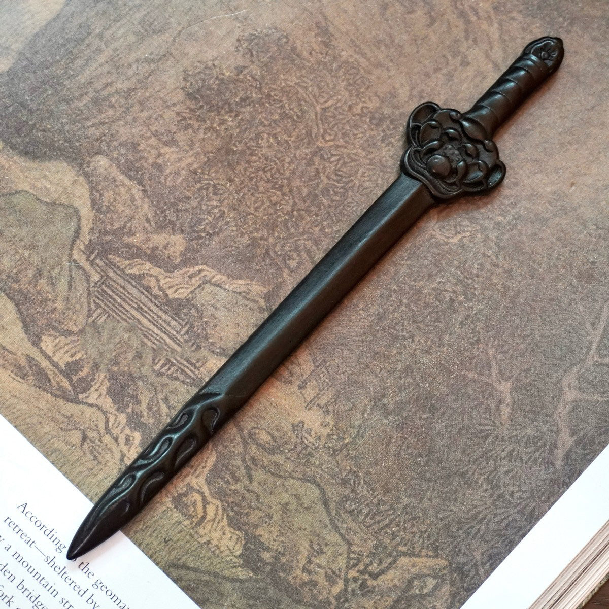 Natural African Blackwood hair stick with lotus sword (Lian Ling Jian) design 17.5cm on vintage book background.