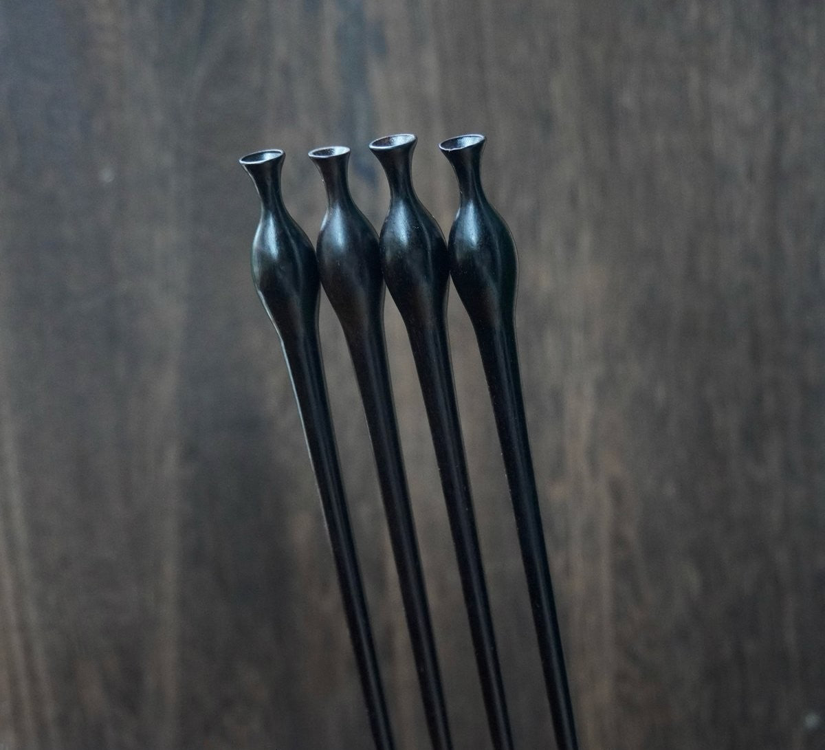 Natural African Blackwood hair stick with vase (flower bottle) design against blurred background.