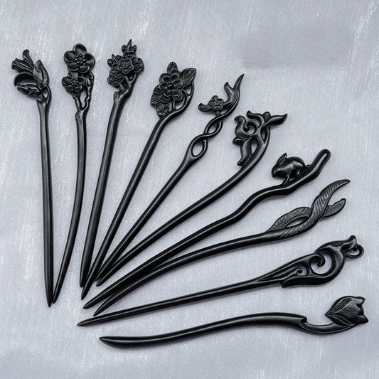 Set of 10 natural African Blackwood hair sticks with carved floral, bird, and animal designs on a light background.
